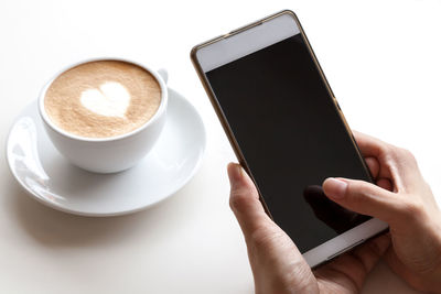 Close-up of hand holding coffee cup on table