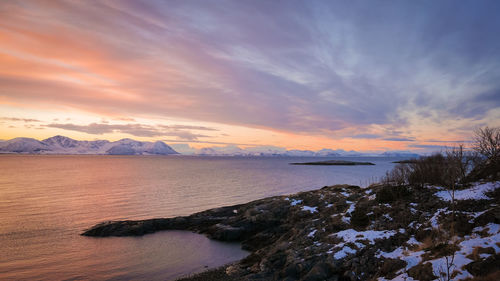 Scenic view of river against cloudy sky during sunset