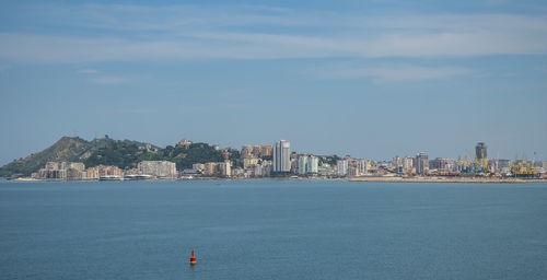 Sea by buildings against sky in city