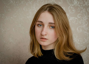 Portrait of a beautiful young woman against wall