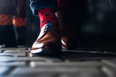 Low section of man wearing shoes while walking on cobblestone