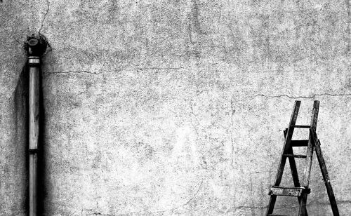 Ladder and pipe against abandoned wall