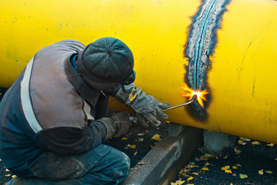 Side view of man working on yellow