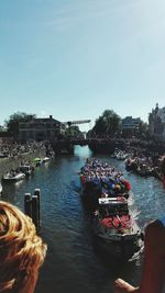 People sailing on river in city against clear sky