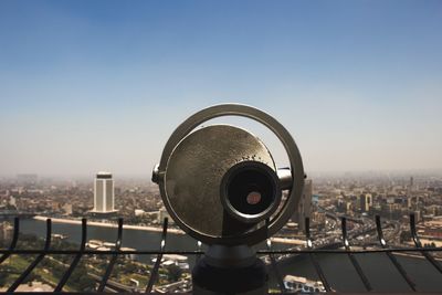 Close-up of coin-operated binoculars against cityscape