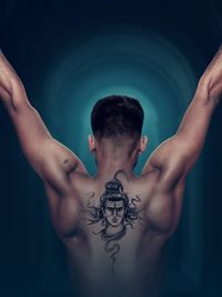 Rear view of shirtless man with arms raised