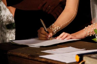 Cropped image of bride signing document during wedding ceremony