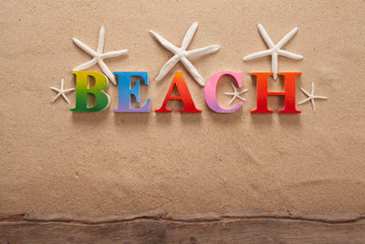 Directly above shot of beach text with seashells on sand at beach