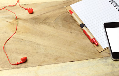 High angle view of book with mobile phone and headphones on wooden table