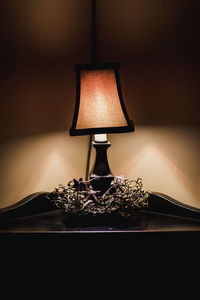 Close-up of illuminated lamp on table against wall
