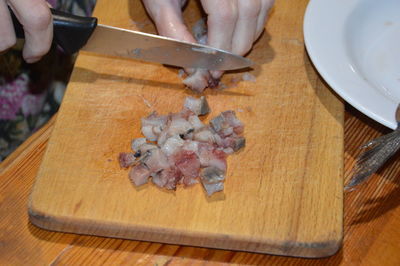 Slicing herring with a knife on a the kitchen board