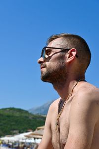 Young man looking away against clear blue sky