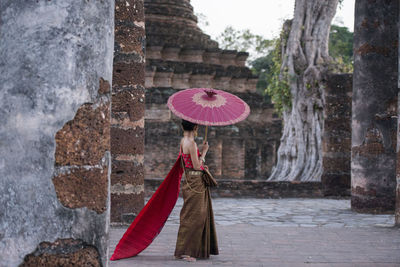 Woman with red umbrella against brick wall