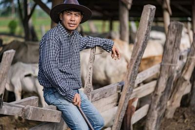 Young man looking away while standing on wood