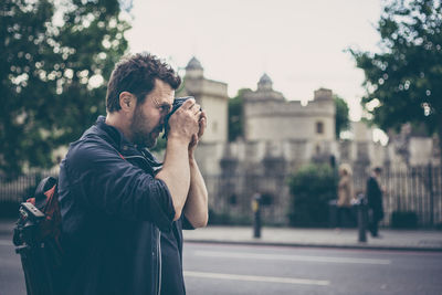 Midsection of man photographing while standing on city street