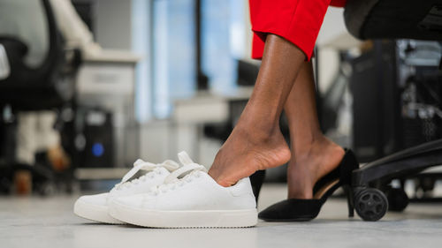 African american woman takes off her shoes in the office.