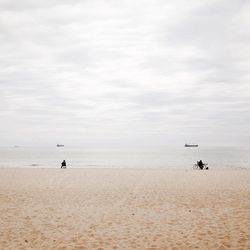 Rear view of men at beach against sky