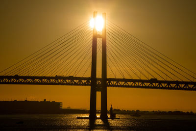 View of suspension bridge over river at sunrise