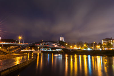Illuminated bridge over river against sky at night