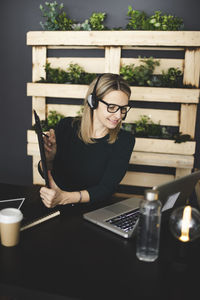 Young woman using mobile phone while sitting on table