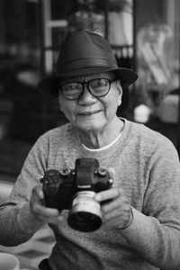 Portrait of man wearing hat holding camera