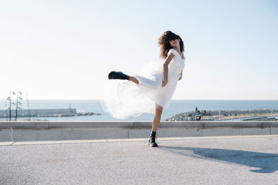 Full length of woman standing in city against clear sky