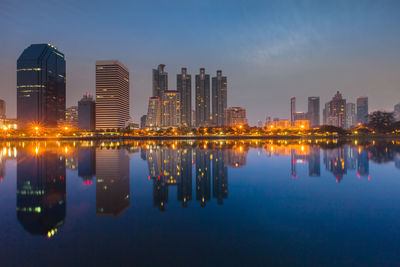 Reflection of illuminated buildings in river against sky