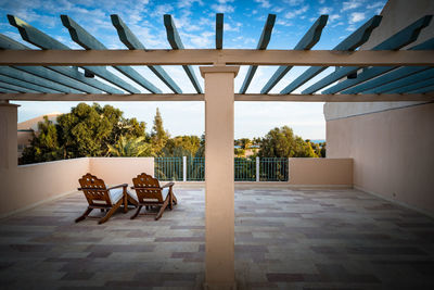 Empty chairs and table against the sky