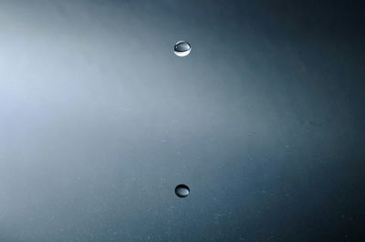 Close-up of water drops falling against gray background