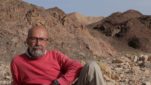 Senior man sitting on rock in the desert 