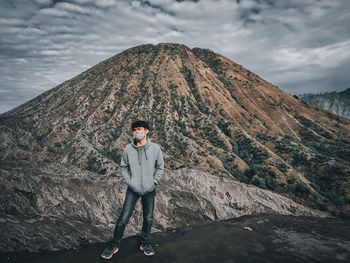 Portrait of young man standing on mountain against sky