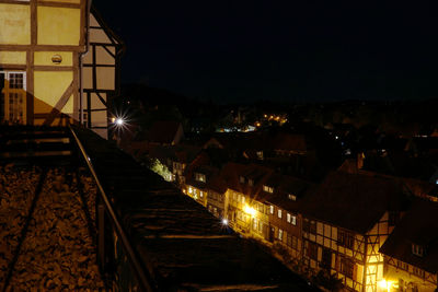 High angle view of illuminated railroad tracks amidst buildings at night