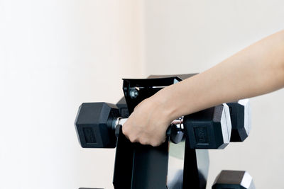 Cropped hand holding dumbbell in gym