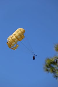 Low angle view of person parachuting against clear blue sky