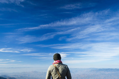 Rear view of man standing on mountain against sky