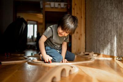 Boy playing with toy on hardwood floor at home