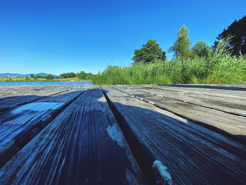 Surface level of empty road against clear blue sky