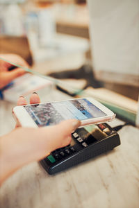 Woman paying for medicines at pharmacy using contactless method of payment via mobile phone