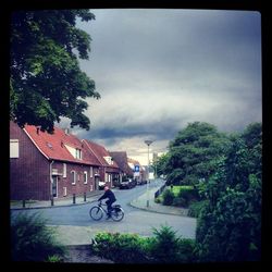 Houses on road against cloudy sky