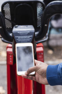 Hand of man renting bicycle through smart phone at parking station