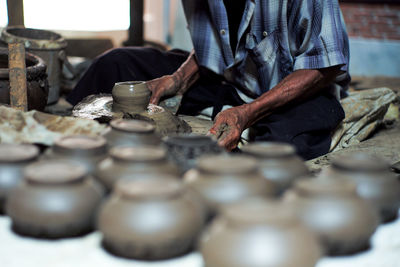 Midsection of man working the clay pottery