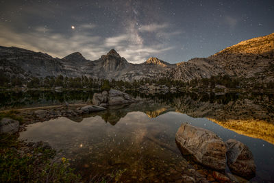 Scenic view of lake and mountains against sky at night