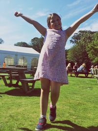 Happy girl with arms raised on field in yard