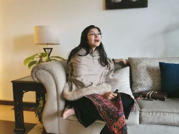 Young woman sitting on sofa at home