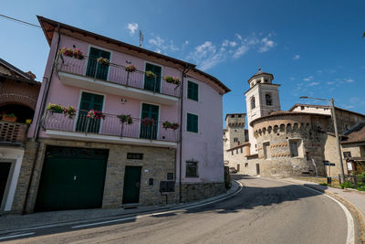 Buildings by street against sky
