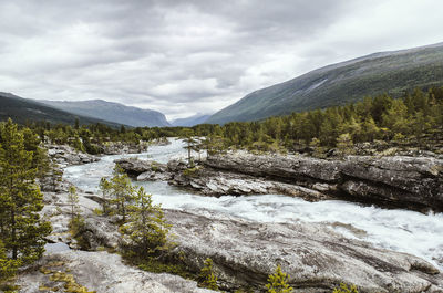 Scenic view of river and mountains against sky