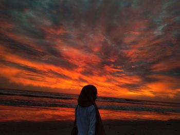Woman looking at sea against sky during sunset