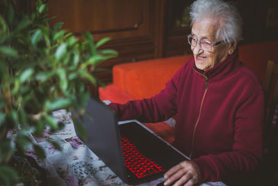 Smiling senior woman using laptop while sitting at home