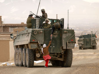 Army soldiers with armored vehicle on road against sky