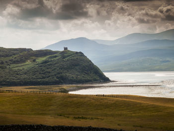 Scenic view of lake and mountains against cloudy sky